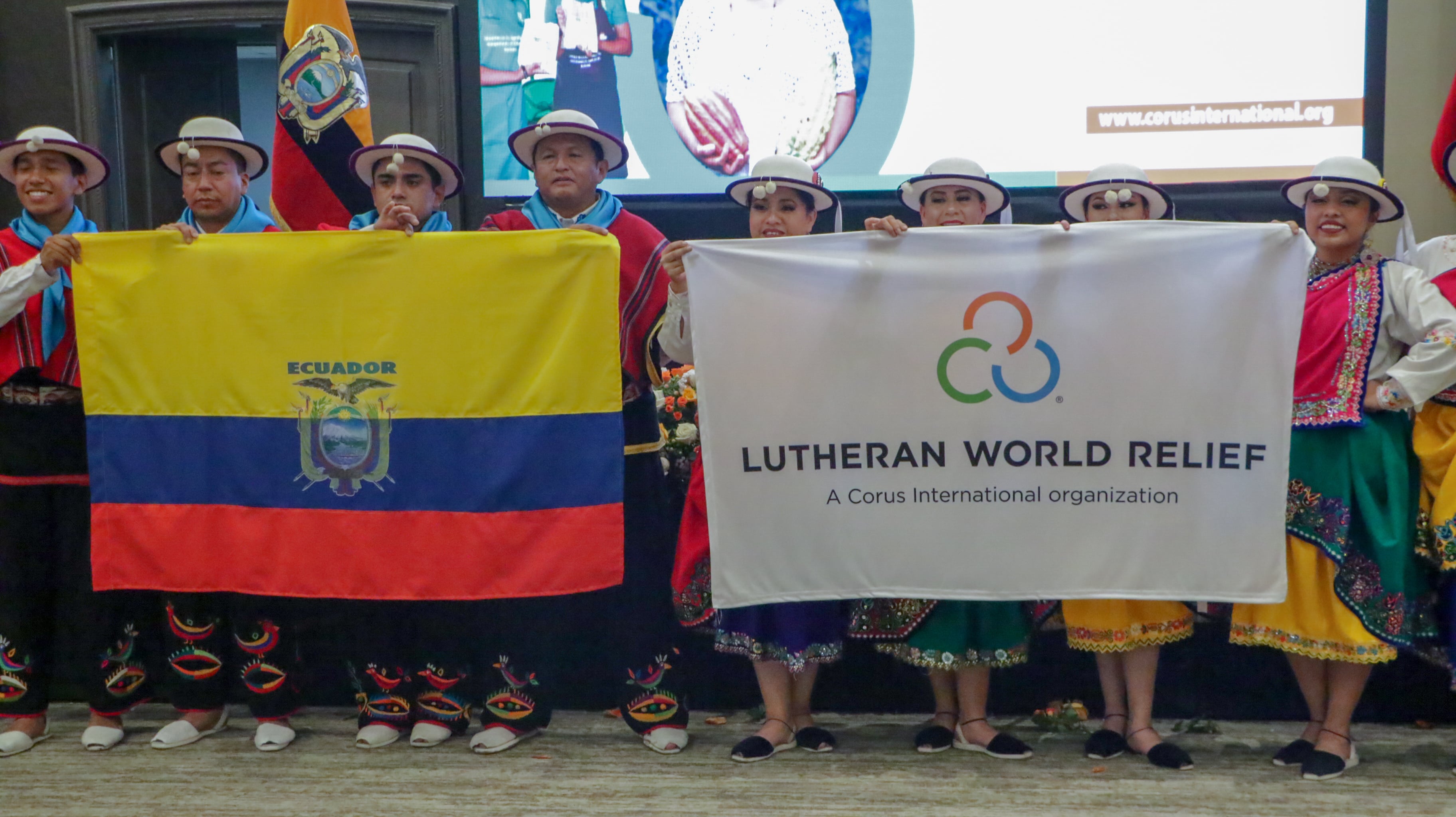 Ecuador and LWR flags held by dancers in traditional Ecuador costume.