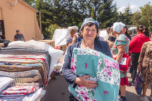 a Ukrainian holding a quilt and smiling at the camera.