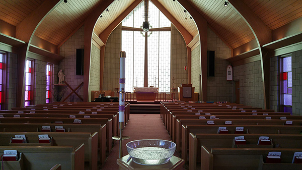 A church sanctuary with light filtering in large windows