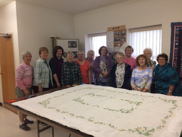 The quilters at Bristol Lutheran Church gather around a completed quilt. The group is known for using large sheets of fabric for their quilt tops. 