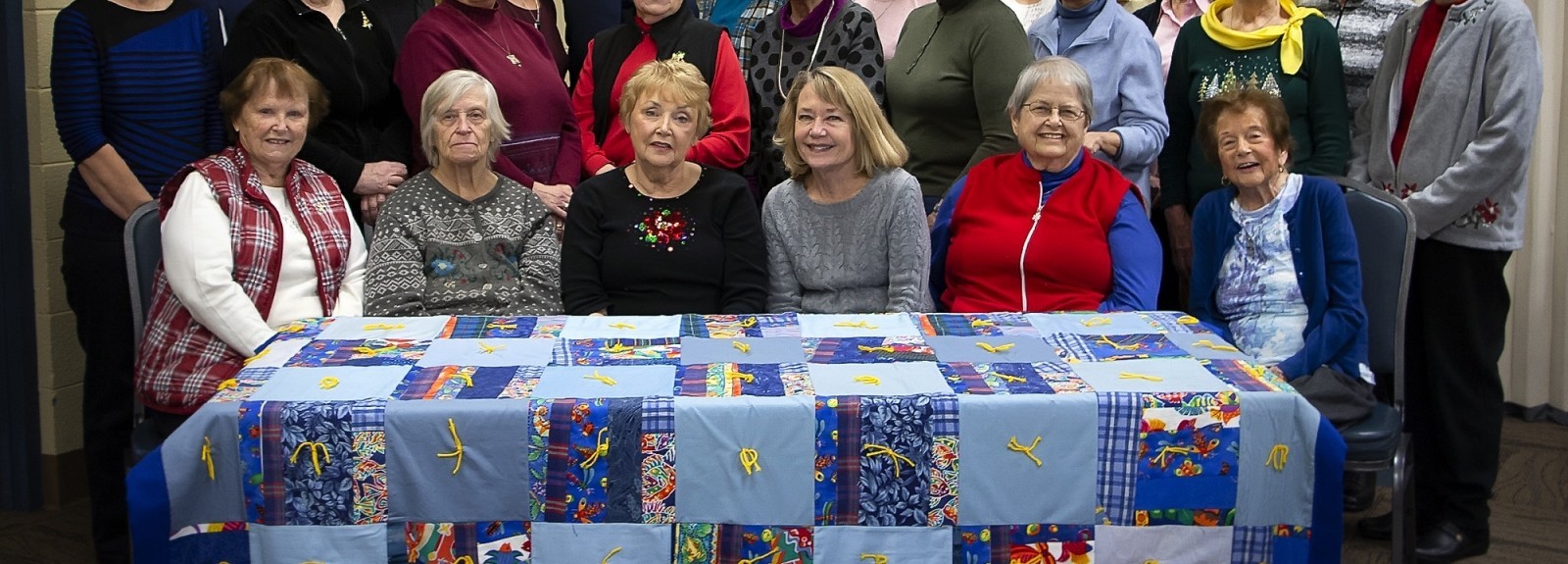 The quilting group at Gethsemane Lutheran Church in Hopkins, Minn. pose with a beautiful quilt they created.