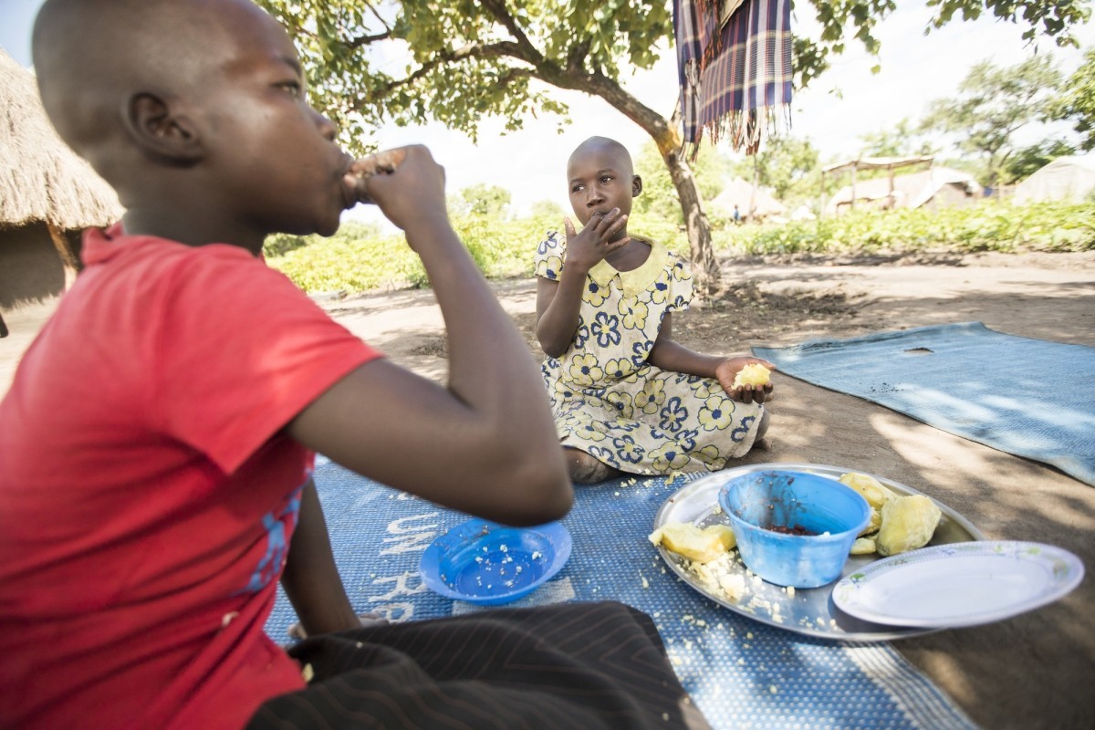 Lakisa Olivia (8, r) and her sister, Ajara Tracy (12, l) eat nutritious sweet potatoes harvested from their mother’s garden in Palabek Refugee Settlement in northern Uganda.