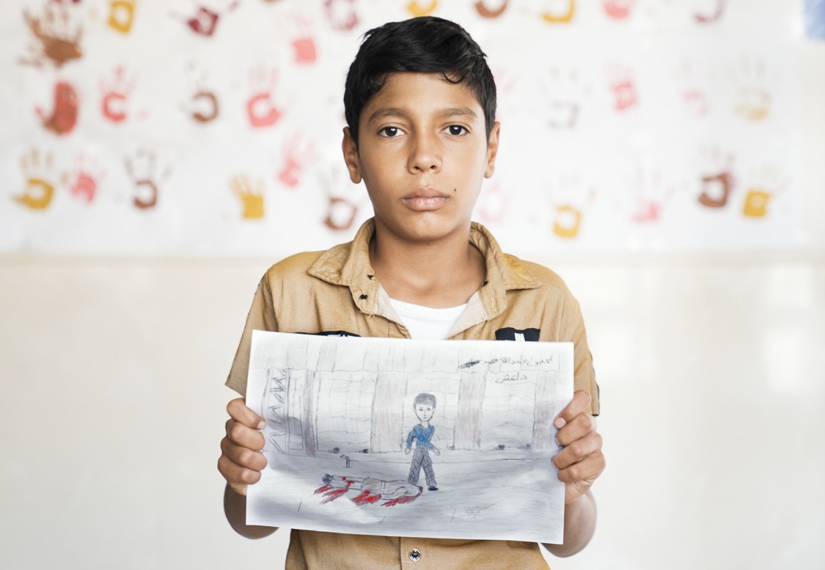 A young boy holds a graphic picture he drew of a man killed by Islamic State militants in Iraq