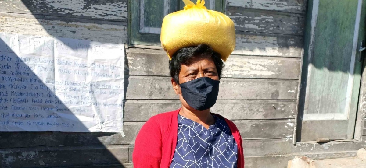 Astaria Br Ginting carrying food distributed by the project. She and her husband manage their farm and sometime sell their products in a nearby weekly market.