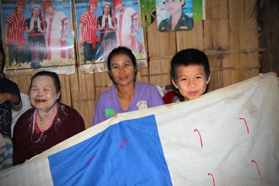 A family displays one of their LWR Quilts inside their bamboo shelter at Mae La, the largest of nine camps that serve Burmese refugees along the Thai-Burma border.