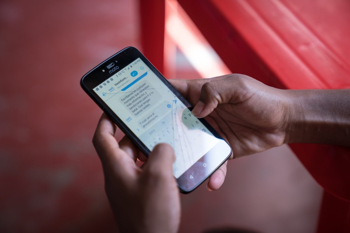 Close up of hands holding cell phone showing VenInformado platform