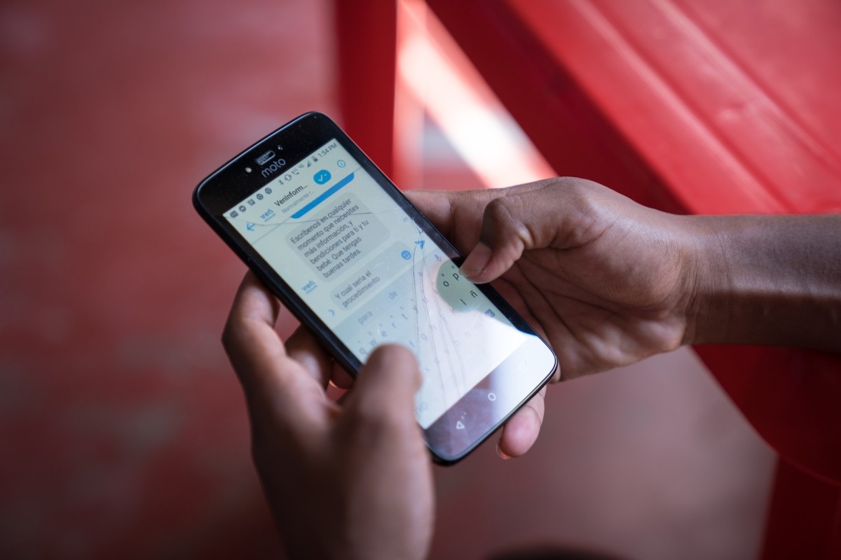 Close up of hands holding cell phone showing VenInformado platform 