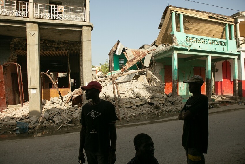 Haitians stand in the ruined streets of their community. 