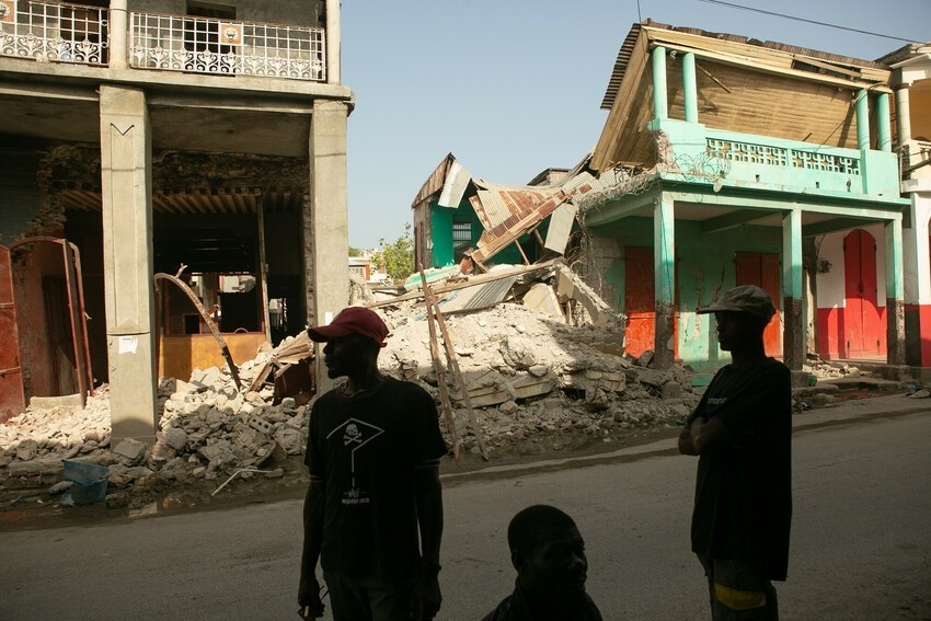 Haitians stand in the ruined streets of their community.