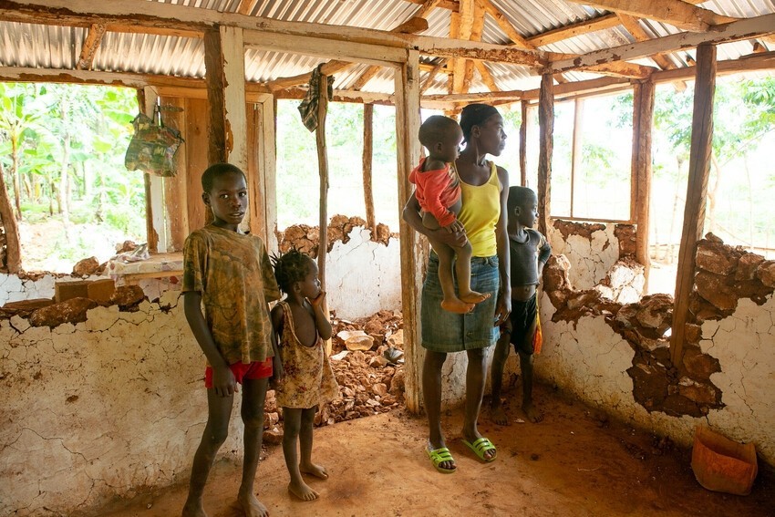 Haitian family stand inside their ruined home. 