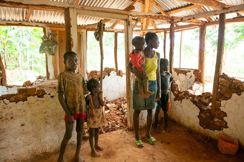 Haitian family stand inside their ruined home.