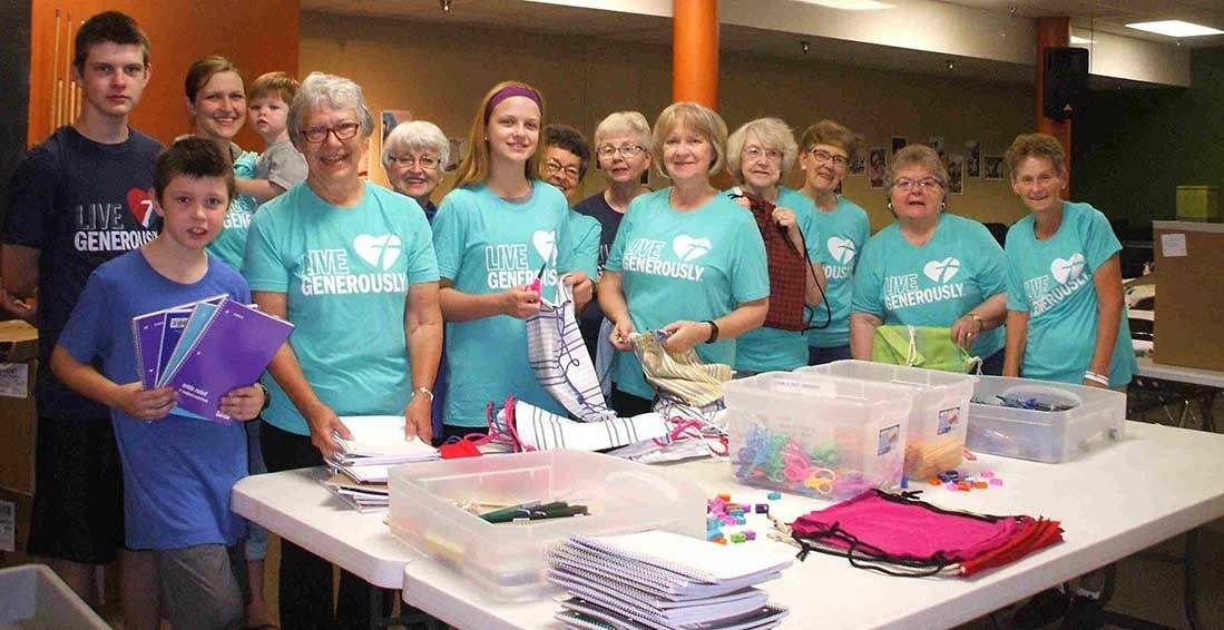 A group of adults and children stand in front of items for kits