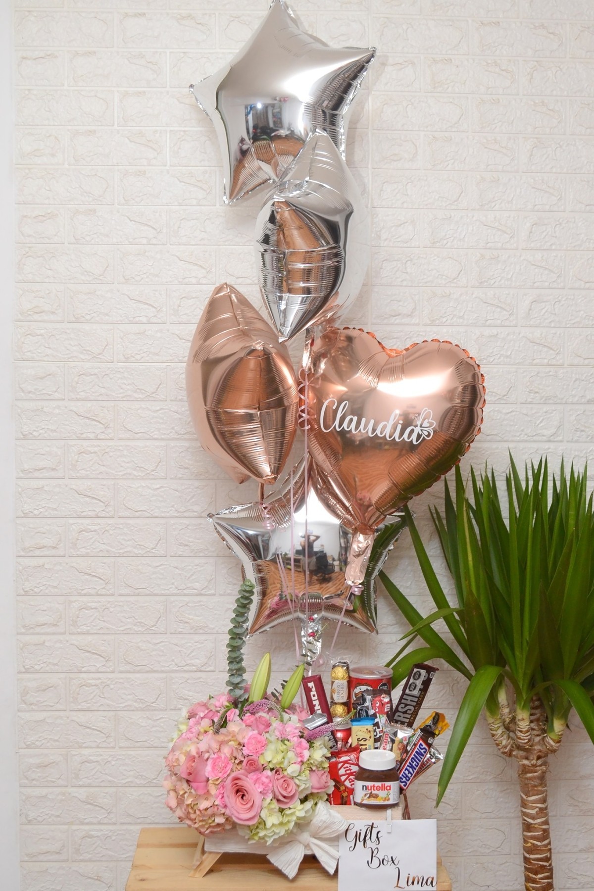 Gift with balloons, candy bars and a pink flower bouquet