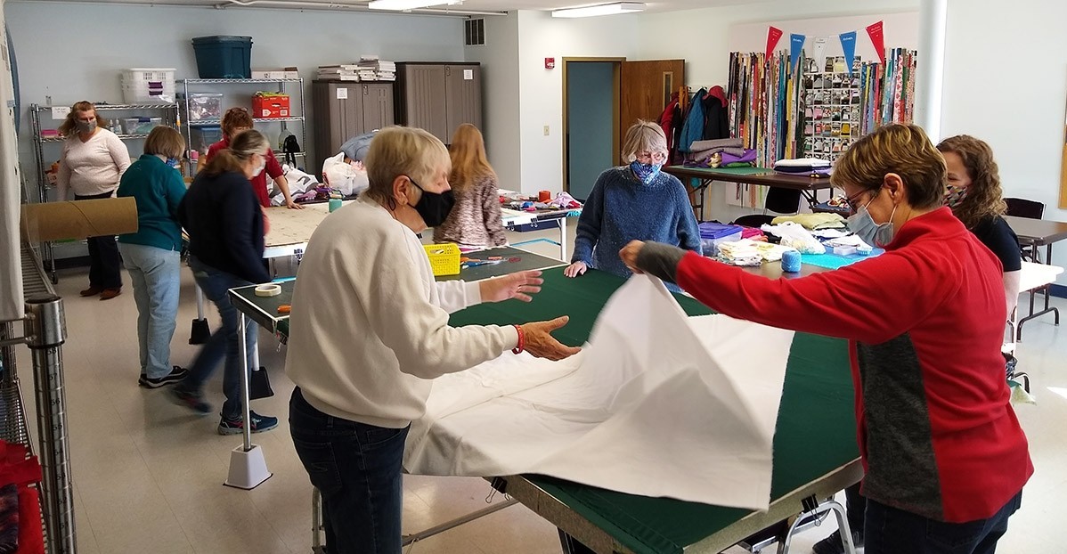 A group of women unfold fabric.