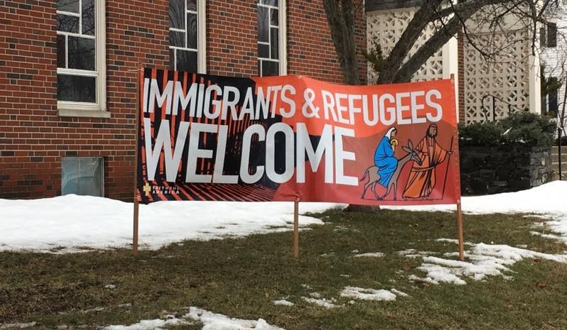 Outdoor sign reads "Immigrants and refugees welcome"