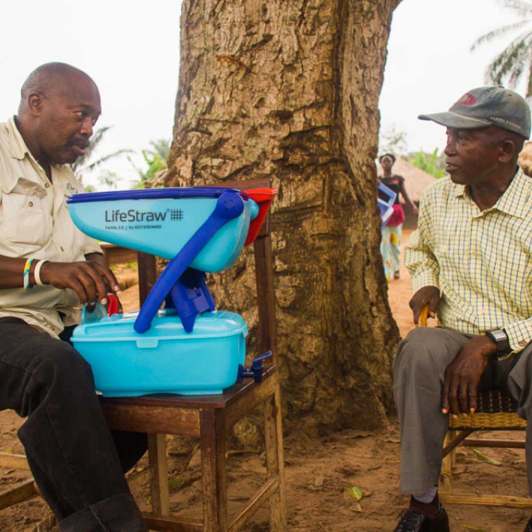 IMA consultant Woody Collins teaches a villager how to use his new household LifeStraw filtration system. (Photo by Crystal Stafford, for IMA World Health)