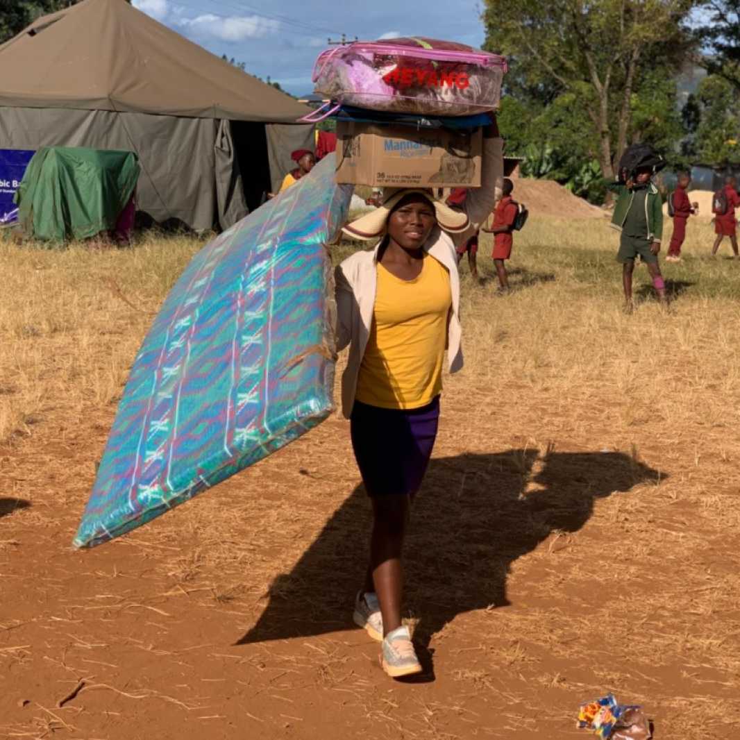 A woman carries a mattress and other items she received from a distribution carried out by our local partner, Smile for Africa, and made possible by you. (Photo courtesy of Smile for Africa)
