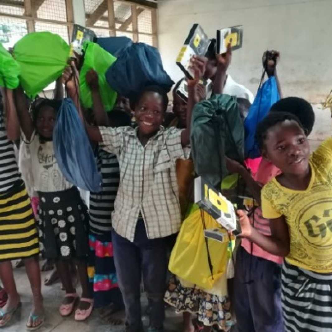 A class of students happily displays their new LWR School Kits in Mozambique. (Photo courtesy of Save the Children)