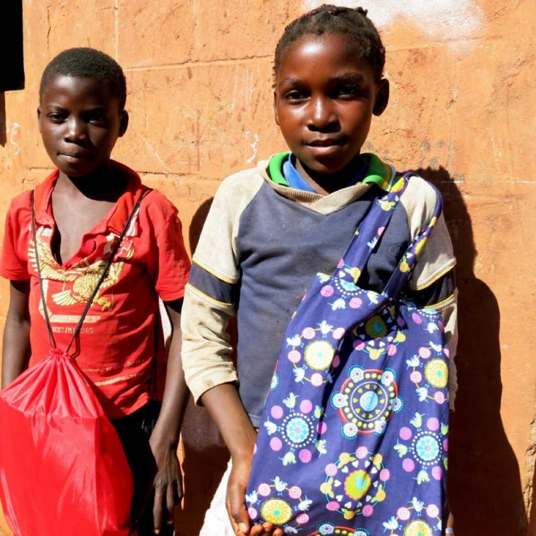A boy and a girl happily display the LWR School Kits they received during a distribution in Mozambique. (Photo courtesy of Save the Children)