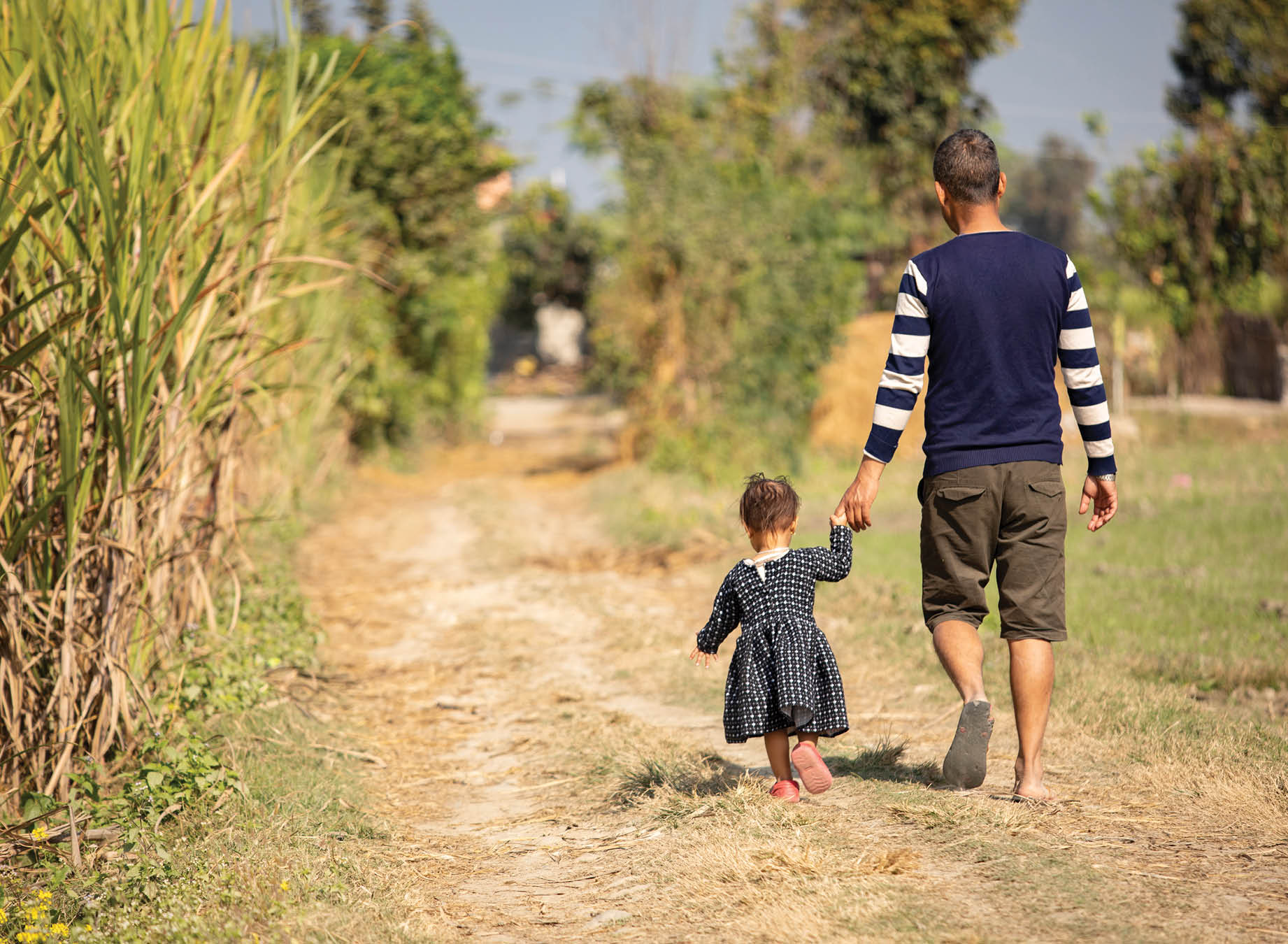 A father and daughter walk down the road in Nawalparasi District, Province No  5, Nepal  LWR works through the Transboundary Flood Resilience Project to prepare communities in the Naranyi and Koshi river basins for impending floods during the monsoon season and enables them to recover quickly from the shocks to their livelihoods  Transboundary Flood Resilience Project December 7, 2019 - Nawalparasi District, Province No  5, Nepal  Photo by Jake Lyell for Lutheran World Relief 
