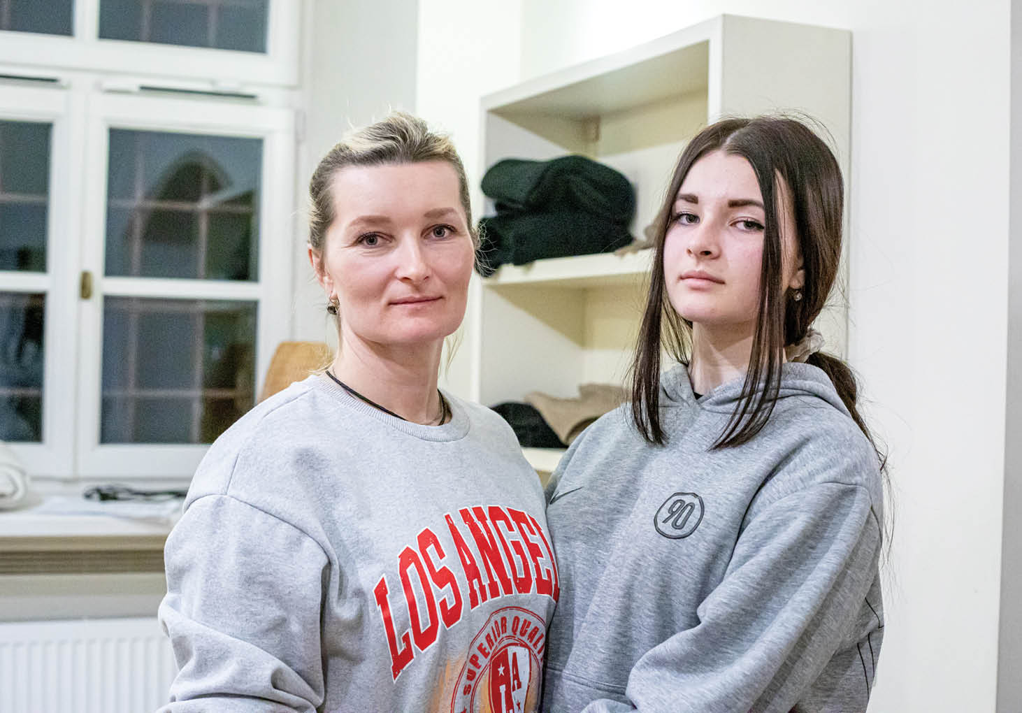 Andryshchenko Svitlana, 47, with one of her two daughters, Hanna Dyniak, 14, in the St  Martin's Lutheran Church makeshift refugee hostel  She is a mother from south Ukraine  She has 2 daughters and had to leave her husband behind due to the restrictions on men leaving the country  She left because she heard the violence was spreading  She arrived in Lviv and then traveled to Krakow and was sent to St  Martin s  Her mother and sister are also still in Ukraine because they were afraid to leave  She emphasized the kindness that they have received from so many people and how they are lucky to have everything they need here in the church while so many others are stuck in Ukraine struggling to access basic needs  Pastor Łukasz Ostruszka and his congregation converted the basement of the church into a safe haven for refugees arriving from Ukraine following the Russian invasion  They are able to house 25-30 refugees at a time and are providing beds, towels, blankets, food, hygiene products, and toys  They were able to renovate the bathroom to include a shower  LWR is supporting St  Martin's by providing room dividers, milk, high energy biscuits, soap, feminie hygiene products, toothpaste and toothbrushes, diapers, and toys  Supplies was delivered in the evening of March 12 in response to the March 11 arrival of over 30 refugees to the church 