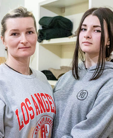Andryshchenko Svitlana, 47, with one of her two daughters, Hanna Dyniak, 14, in the St  Martin's Lutheran Church makeshift refugee hostel  She is a mother from south Ukraine  She has 2 daughters and had to leave her husband behind due to the restrictions on men leaving the country  She left because she heard the violence was spreading  She arrived in Lviv and then traveled to Krakow and was sent to St  Martin s  Her mother and sister are also still in Ukraine because they were afraid to leave  She emphasized the kindness that they have received from so many people and how they are lucky to have everything they need here in the church while so many others are stuck in Ukraine struggling to access basic needs  Pastor Łukasz Ostruszka and his congregation converted the basement of the church into a safe haven for refugees arriving from Ukraine following the Russian invasion  They are able to house 25-30 refugees at a time and are providing beds, towels, blankets, food, hygiene products, and toys  They were able to renovate the bathroom to include a shower  LWR is supporting St  Martin's by providing room dividers, milk, high energy biscuits, soap, feminie hygiene products, toothpaste and toothbrushes, diapers, and toys  Supplies was delivered in the evening of March 12 in response to the March 11 arrival of over 30 refugees to the church 
